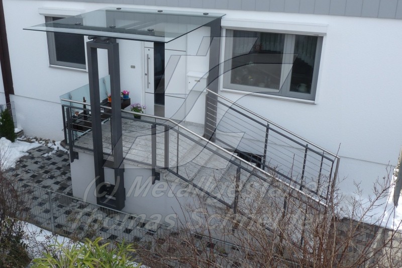 Der Eingangsbereich wurde mit einer bruchsicheren Glasplatte überdacht und lässt weiterhin genügend Licht in den Flur fallen. Zusätzlich wurde ein individuelles Design-Metallgeländer mit Edelstahl-Handlauf verwendet.